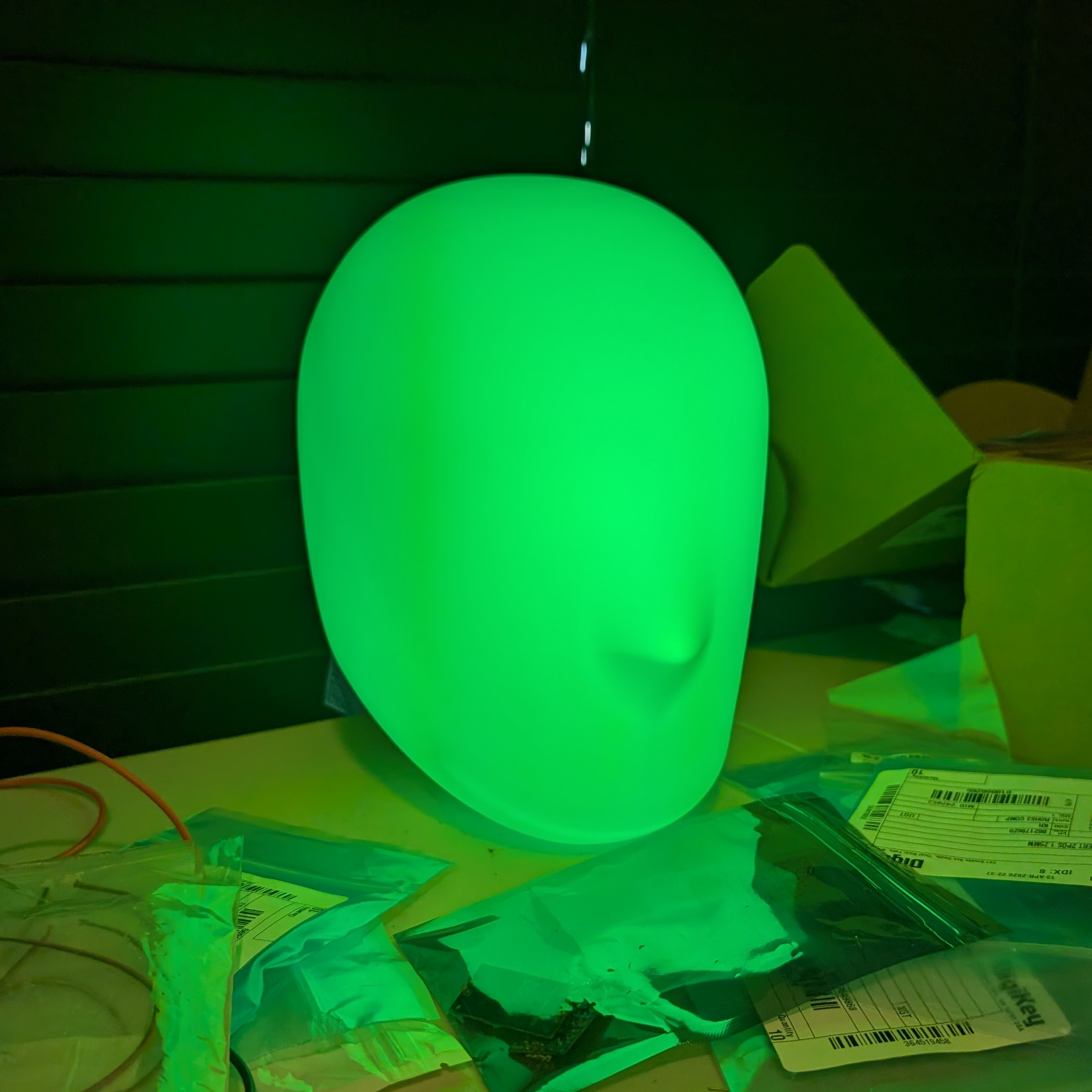 A CHaaS lamp on a desk - head shaped and glowing green